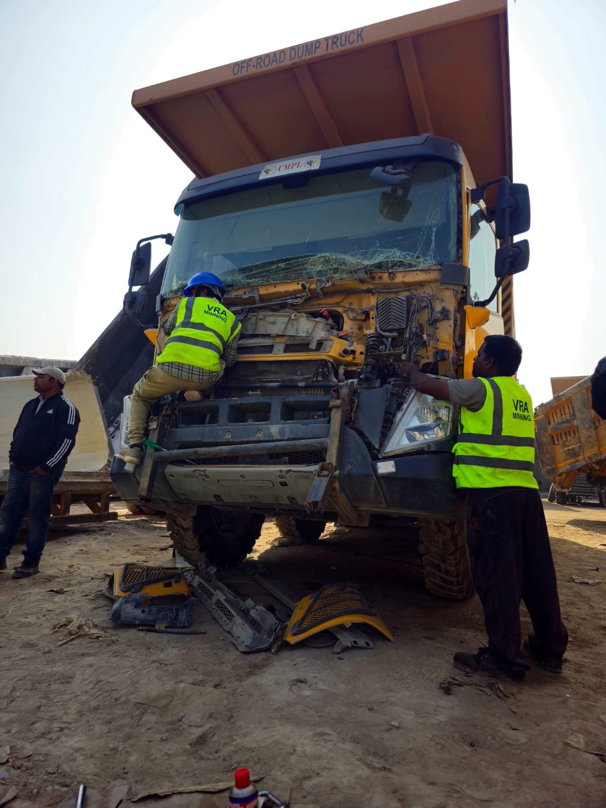 VRA Mining technicians in hi-vis vests working on the damaged front end of an off-road dump truck